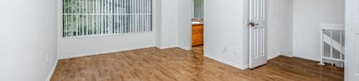 an empty living room with wood flooring and a large window