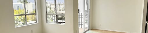 A room with a wooden floor and a view of the outside through the windows.