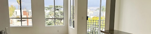 A room with wooden flooring and a view of the outside through the windows.