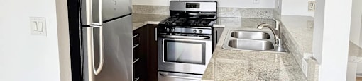 A kitchen with a stainless steel refrigerator, microwave, oven, and sink.