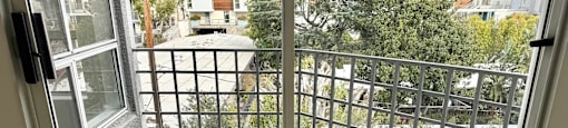 A balcony with a metal railing and a view of a residential area.