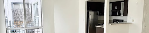 A kitchen with a refrigerator, microwave, and oven is visible through a doorway.