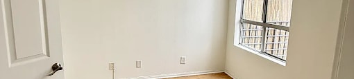 A room with a white door and wooden flooring.