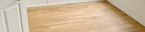 A room with a white door and wooden flooring.