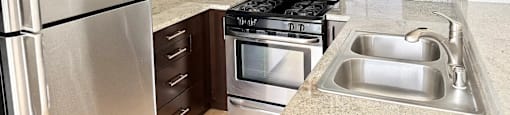 A kitchen with a stainless steel refrigerator, microwave, oven, and sink.