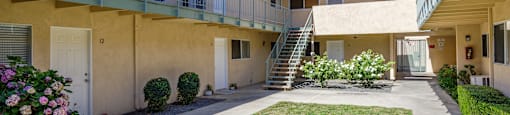 the courtyard of an apartment building with a lawn and a staircase