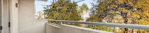 A balcony with a grey floor and a white wall.