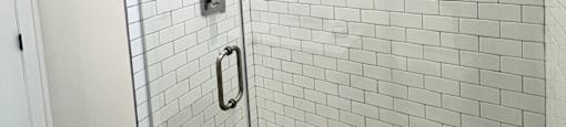 a walk in shower in a white tiled bathroom