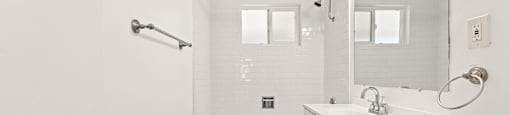 A white bathroom with a tub, sink, and mirror.