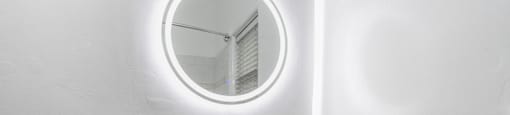 a white bathroom with a white sink and a white mirror