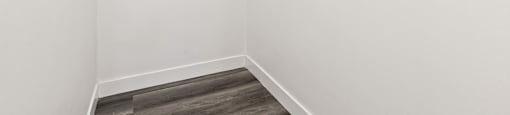 A white closet with a shelf and a grey floor.