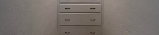 a small closet with white drawers and an arched ceiling