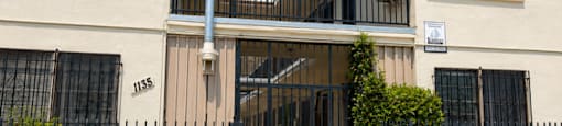 A two-story beige building with black railings and a black gate.