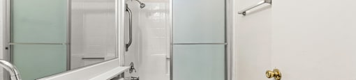 A white bathroom with a sink, toilet, and shower.