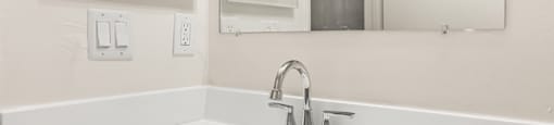 A white bathroom sink with a silver faucet and a mirror above it.
