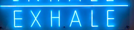 A neon sign that says "inhale exhale" is displayed.