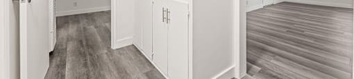 A white interior with wood flooring and a doorway leading to another room.