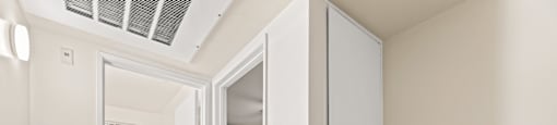 A white door is open to a room with a bed.