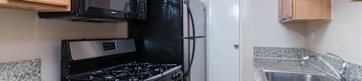 A kitchen with black appliances and wooden cabinets.