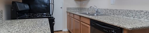A kitchen with a black fridge and stove top oven.