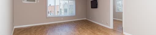 A room with wooden flooring and a window with blinds.