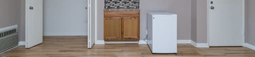 A room with a white fridge and a stone wall.