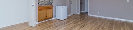 A room with a wooden floor and a white refrigerator.