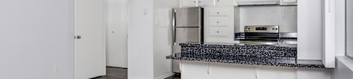 A kitchen with white cabinets and a granite countertop.