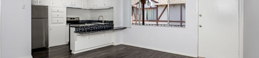 A kitchen with white cabinets and a black countertop.