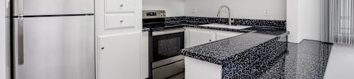 A kitchen with white cabinets and a black granite counter.