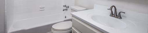 A white bathroom with a toilet, sink, and bathtub.