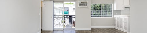 a living room with white walls and a door to a balcony