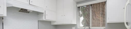 a kitchen with white cabinets and a sink and a window