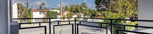 the balcony has a view of the city and palm trees