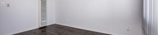 A room with a wooden floor and a window with blinds.