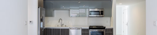 an empty kitchen with stainless steel appliances and white walls