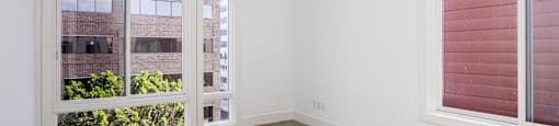 an empty living room with large windows and a concrete floor