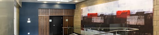 a lobby with a large painting on the wall and a staircase with glass railing
