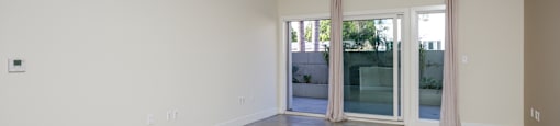 an empty living room with glass doors and a cement floor