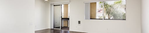 an empty living room with hard wood floors and a window