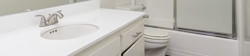 a white bathroom with a shower sink and toilet