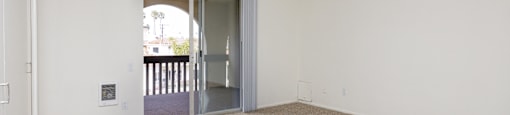an empty living room with an open door to a balcony