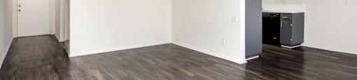 the living room and kitchen of an apartment with hardwood floors and white walls
