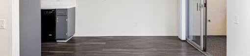 an empty living room with a ceiling fan and a kitchen
