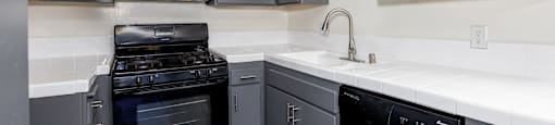 a kitchen with black appliances and white counter tops and gray cabinets
