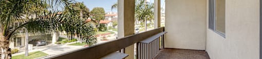a balcony with a view of the street and palm trees