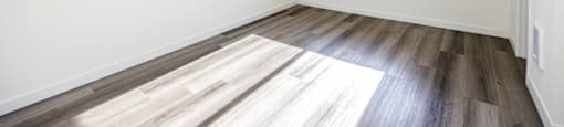 an empty room with wood floors and a window