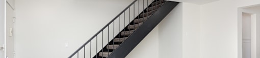 a staircase in a home with white walls and wood floors