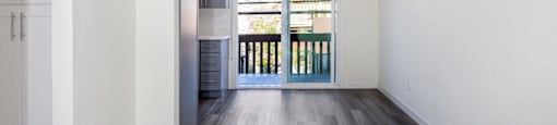 a living room with white walls and wooden floors and a balcony
