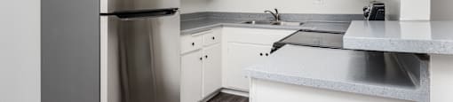 a kitchen with white cabinets and a stainless steel refrigerator